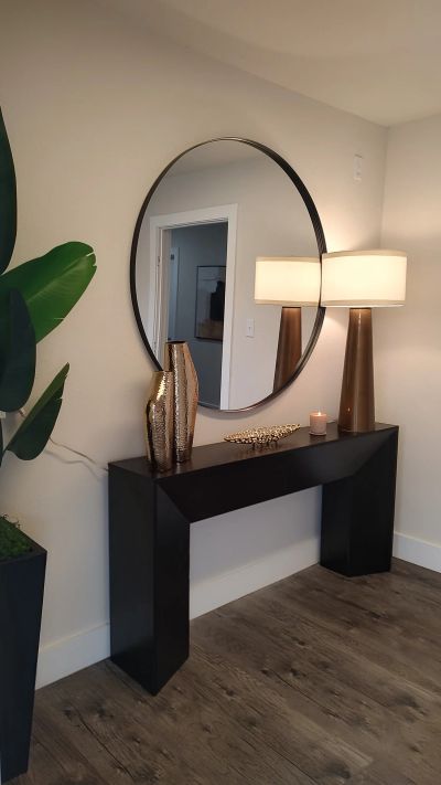 Large round mirror over black console table