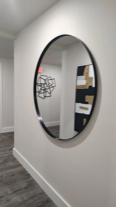 Oval mirror reflecting hallway artwork